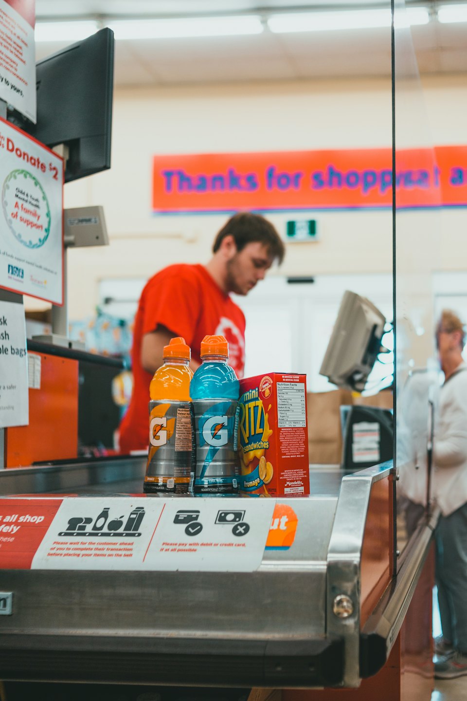 Cashier processes a transaction at a grocery store counter.