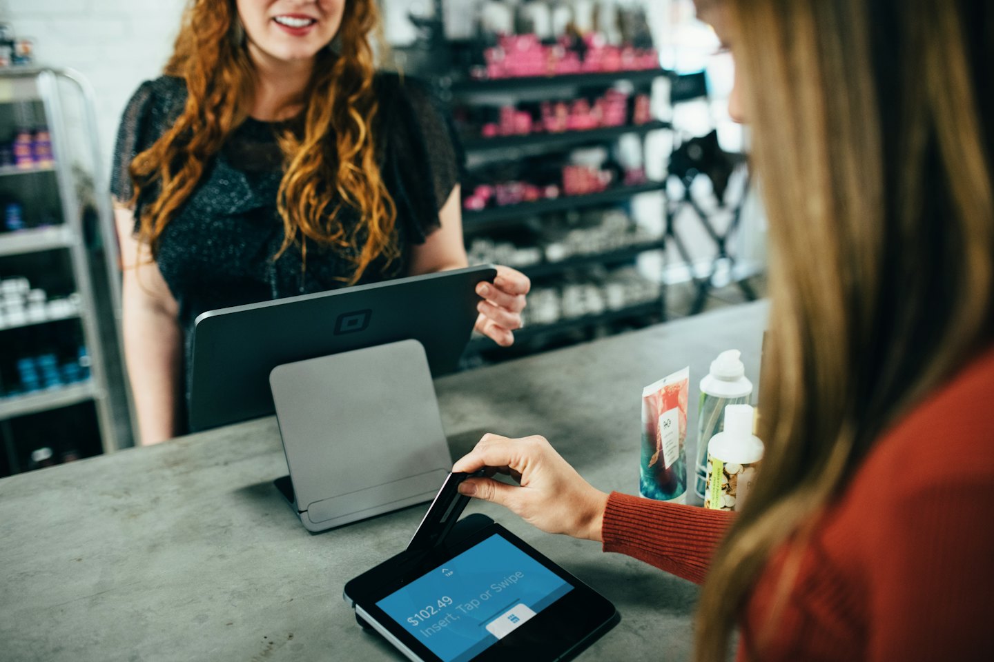 Customer paying with credit card at a black point-of-sale terminal.