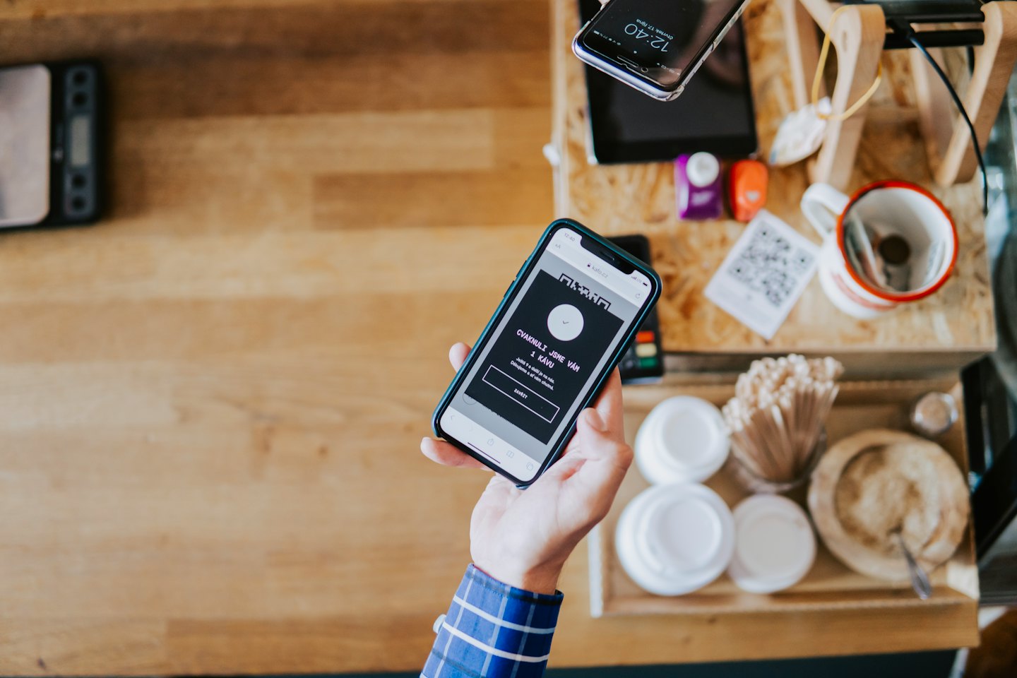 Hand holding smartphone with loyalty program on wooden counter.